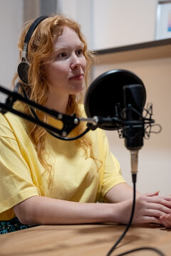 Young lady taking notes and recording radio podcast