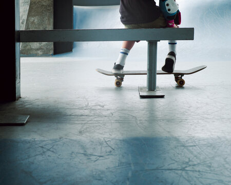 Boy sit on a bench in protective gear with skateboards