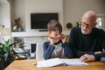 Mature man helping kid with schoolwork