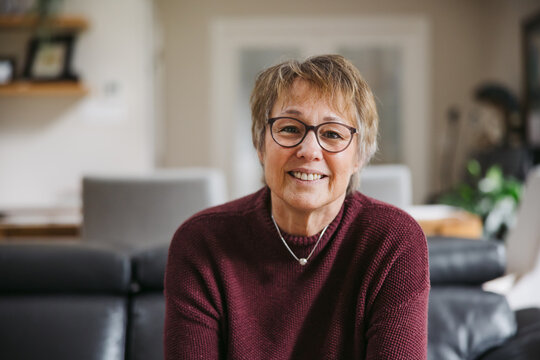 Woman on couch smiling at camera.
