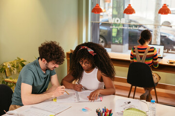 Smart diverse students doing assignment together in cafe