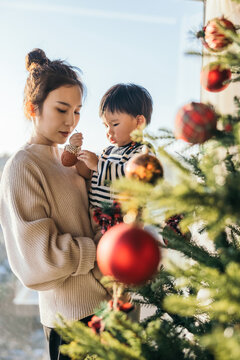mom and son decorating Christmas pine