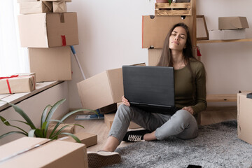 casual beautiful female entrepreneur, teenager business owner work from home, many things in boxes, sleeping with laptop, young woman moves while sitting among cardboard boxes