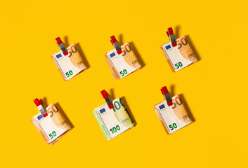 50 and 100 euro notes clipped together on a yellow background
