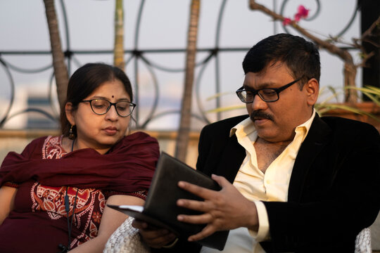 Indian Middle Aged Man Checking Bill In A Restaurant With Wife Beside