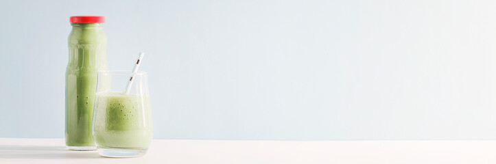 healthy green smoothie in glass, bottle with straw on blue background. Vegetarian healthy lifestyle concept.refreshing drink. copy space banner