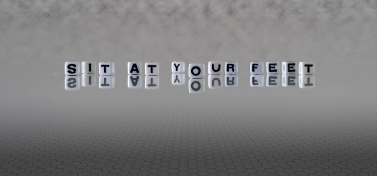 sit at your feet word or concept represented by black and white letter cubes on a grey horizon background stretching to infinity