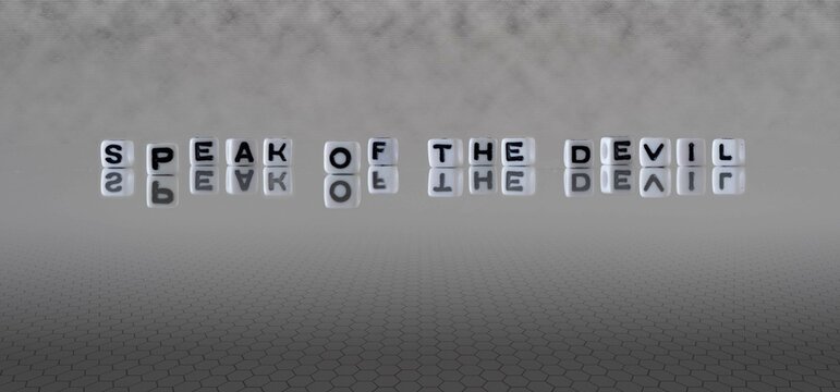 speak of the devil word or concept represented by black and white letter cubes on a grey horizon background stretching to infinity