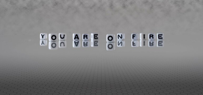 you are on fire word or concept represented by black and white letter cubes on a grey horizon background stretching to infinity