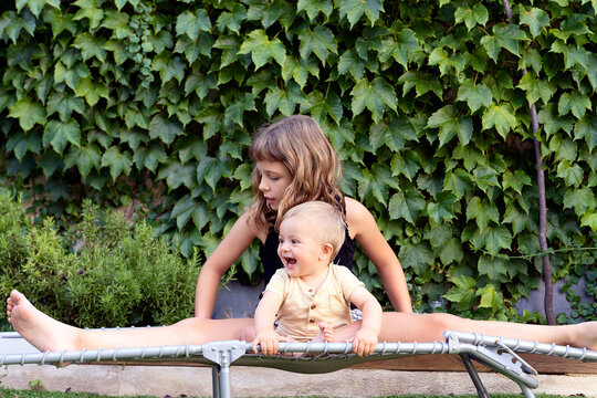 Playful baby with sister on comp bed in yard