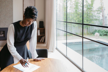 Professional confident woman at home reading and signing documents
