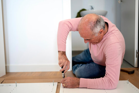 Senior man assembling furniture with screwdriver