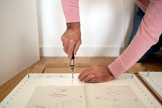 Elderly man using tool and assembling furniture