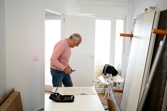 Elderly man assembling furniture at home