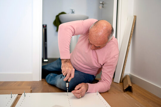 Aged man assembling furniture at home