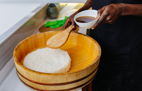 Crop person mixing sushi rice in wooden bowl