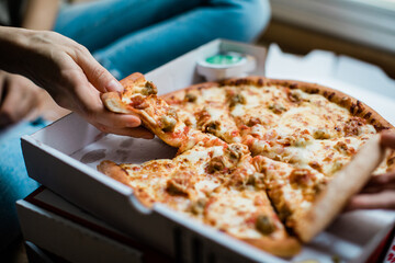 Hand grabbing a slice of pizza.