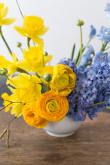 Flower arrangement on japanese holder kenzan for home. Seasonal spring blue and yellow flowers, set for interior.