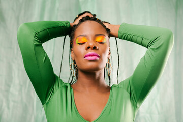 Woman in green with braided hair and creative colorful makeup