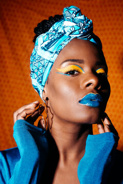 Girl with African print headband and creative makeup looking at camera