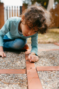 Curious Kid observing  a bug on the ground in a garden