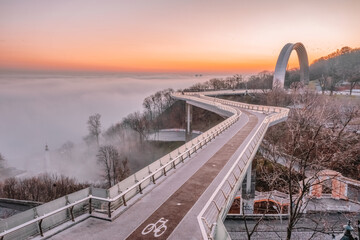 Pedestrian bicycle bridge, Kyiv Ukraine, dawn, heavy fog spreads over the Dnieper river, aerial view
