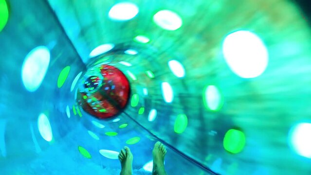 Boy have fun in a closed slider at water Park. Fun on water. Enjoying water slider ride. Rider POV. Point of view in aqua park tube slide. Summer time. Multicolors view