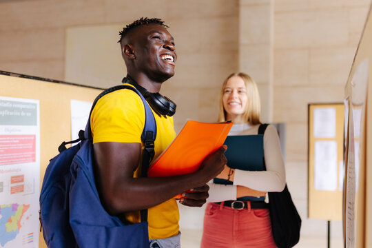 Cheerful black man with backpack with friend at university
