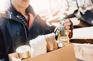 Homeless refugee is holding box with things and food. Concept humanitarian aid community charity donations center