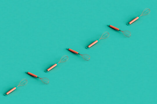 a row of kitchen whisks crossing the frame with copy space