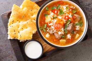 Asian soup with lamb, rice and vegetables close-up in a bowl on a wooden tray. horizontal top view from above