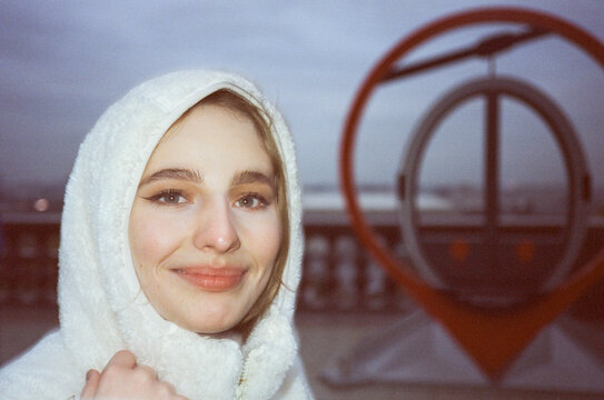 Portrait of woman in white hood next to a here you are symbol 