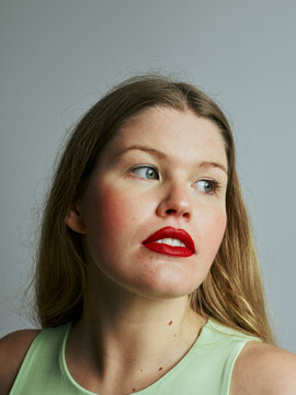 portrait of young blond woman looks away with red lips and red blush