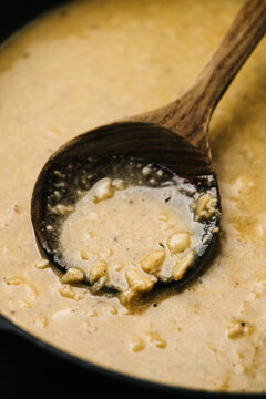 Wooden spoon in creamy garlic sauce