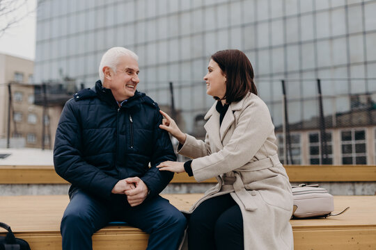 Cheerful colleagues speaking on bench