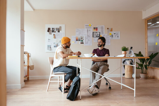 Men Sitting At Table In Creative Workspace