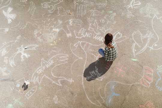 Woman drawing anti-war art with chalk on the street