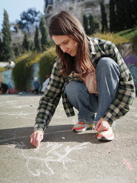 Woman drawing anti-war art with chalk on the street