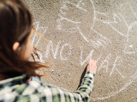 Woman drawing anti-war art with chalk on the street