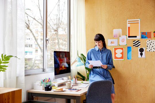 Female freelancer reading paper in home office