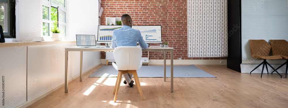 Poster businessman analyzing financial graphs on computer at desk