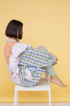 Anonymous woman sitting on stool - side view studio portrait 
