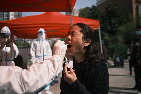 Asian Woman Receives A Throat Swab At A Community Testing Centre.