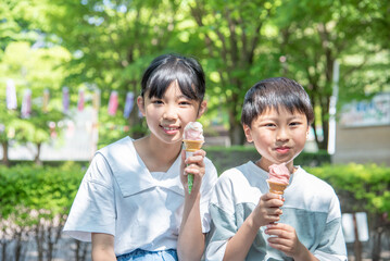 新緑の公園でソフトクリームを食べるアジア人の子供
