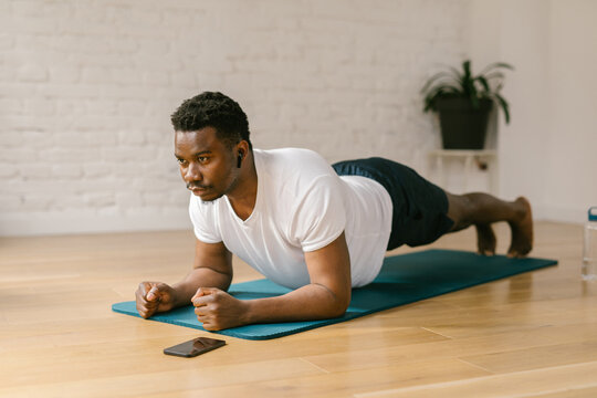 Fit male doing plank exercises indoors