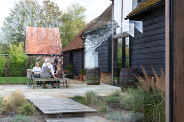 Family having lunch in the patio area of their garden. Looking through