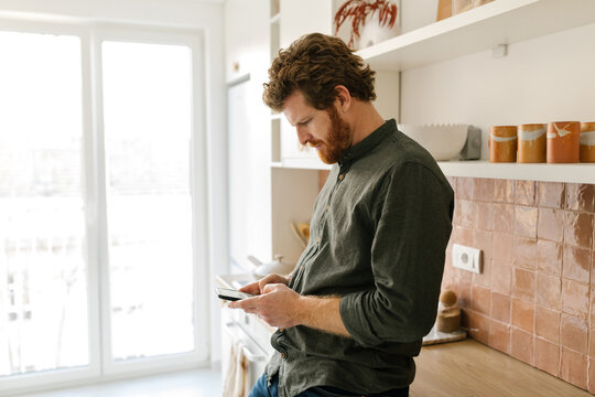 Mature adult man using cellphone at home