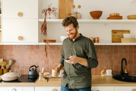 Happy man having cup of coffee and looking at phone