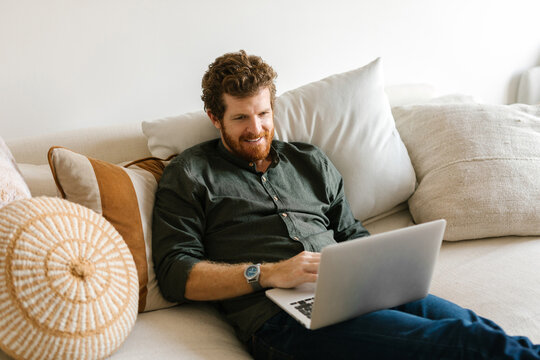 Smiling man browsing on his computer at home