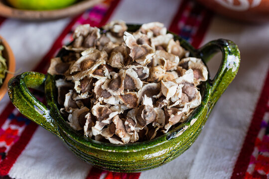 Moringa seeds inside a green clay bowl 